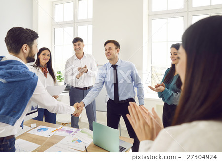 Business people shaking hands finishing meeting and making a good deal standing in office 127304924