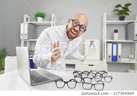 Ophthalmologist, funny smiling doctor showing eye chart, smiling in clinic, helping to choose 127304994