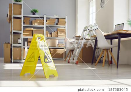 Yellow Sign Caution, Wet Floor In Empty Warehouse 127305045