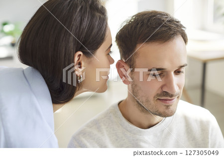 Secret sharing, chatty woman, talkative wife telling news to man, husband, whispering at ear 127305049
