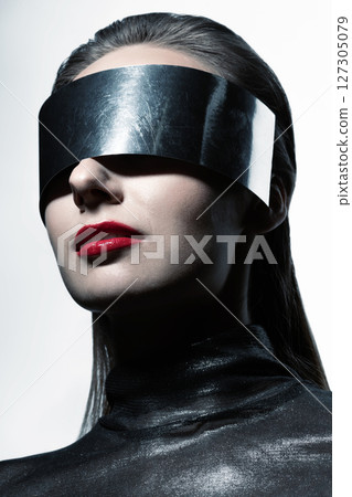 Abstract woman studio portrait with make-up and metallic eyeglasses or helmet covering her eyes 127305079