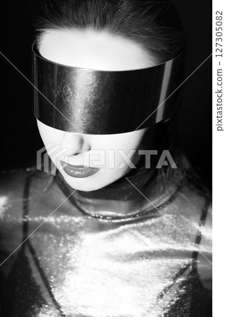 Abstract woman studio portrait with make-up and metallic glasses or helmet covering her eyes 127305082