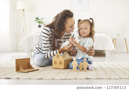 Mother playing with educational wooden toys with cute little child girl in the living room at home 127305113
