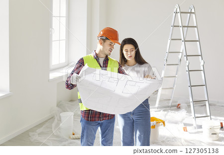 Young woman homeowner discussing design project of her new apartment with a foreman. Young woman homeowner discussing design project of her new apartment with a foreman. 127305138