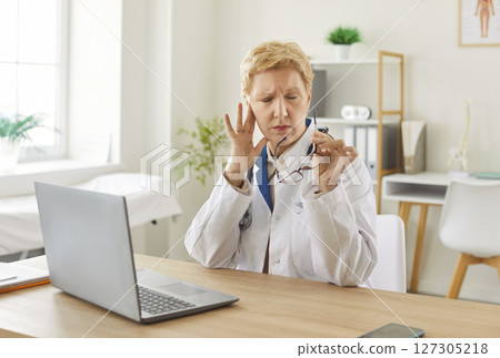 Senior Woman Doctor Or Nurse Experiencing Headache While Working In Hospital 127305218