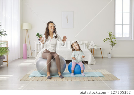 Happy young mother and cute little daughter having workout with yoga balls at home 127305392