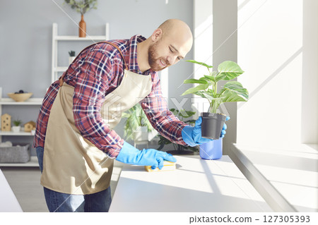Happy smiling male young cleaner wiping desk at home or in office workplace Happy smiling male young cleaner wiping desk at home or in office workplace 127305393