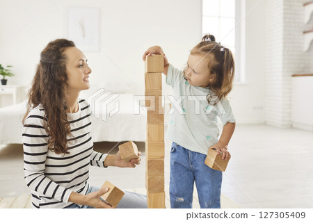 Happy Daughter Playing With Wooden Toys Alongside Her Mother At Home Happy Daughter Playing With Wooden Toys Alongside Her Mother At Home 127305409