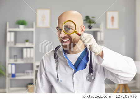 Funny Doctor Or Nurse Smiling While Examining With A Magnifier In Hospital 127305456