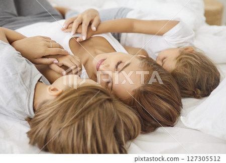 Mother And Kids Sleeping Together In Bed At Home 127305512