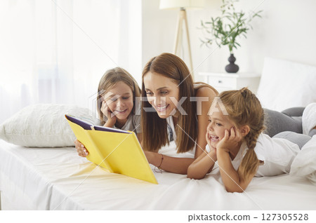 Mother And Kids Enjoying Morning Leisure In Bed Reading A Book At Home Mother And Kids Enjoying Morning Leisure In Bed Reading A Book At Home 127305528
