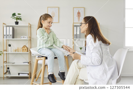 Child patient talking with pediatrician during medical exam in clinic complaining of a sore throat 127305544