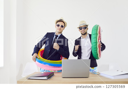 Funny company employees standing in office with rubber ring and going on holiday trip together. 127305569