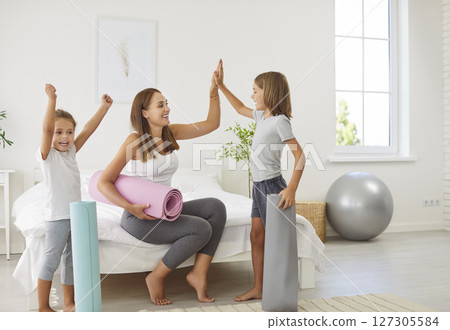 Happy sporty family, fit mother and kids with yoga mats ready to exercise in fitness center 127305584