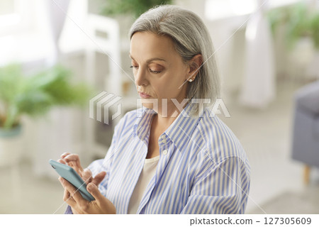 Senior older lady using applications on smartphone, focused old mature woman chatting in messenger Senior older lady using applications on smartphone, focused old mature woman chatting in messenger 127305609