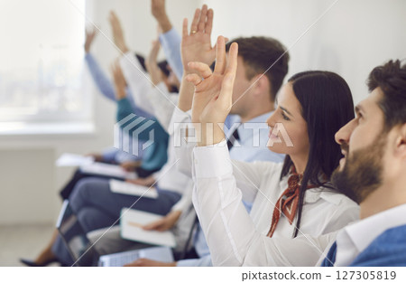 Close-Up Of Business People Raising Hands To Ask Questions During Office Meeting 127305819