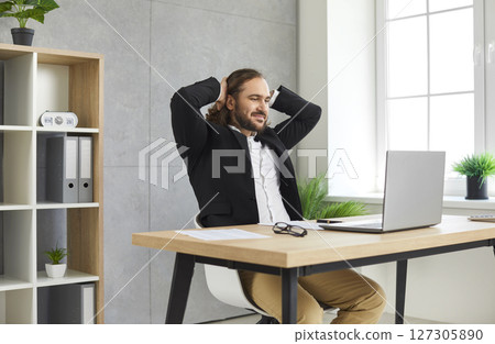 Young confident business man working on a laptop at office looking on computer screen. Young confident business man working on a laptop at office looking on computer screen. 127305890