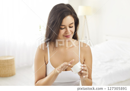 Woman Applying Skincare Cream Or Lotion On Bed At Home 127305891