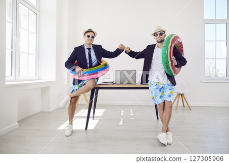 Company employees in sunglasses with rubber rings standing in office ready for summer vacation. Company employees in sunglasses with rubber rings standing in office ready for summer vacation. 127305906