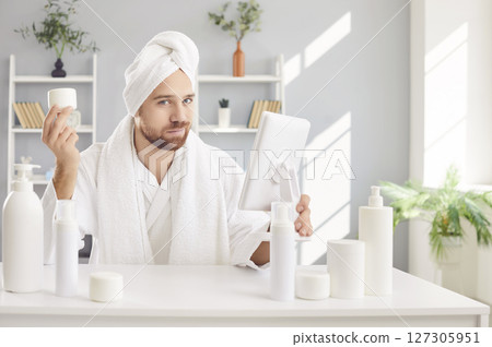 Funny man in bathrobe after shower pretending beautiful, moisturizer on skin, looking in mirror Funny man in bathrobe after shower pretending beautiful, moisturizer on skin, looking in mirror 127305951