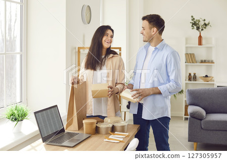Happy smiling young couple unpacking their lunch from takeaway meal delivery service Happy smiling young couple unpacking their lunch from takeaway meal delivery service 127305957