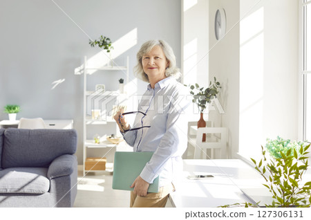 Portrait of confident smiling senior woman standing at home and looking cheerful at camera Portrait of confident smiling senior woman standing at home and looking cheerful at camera 127306131