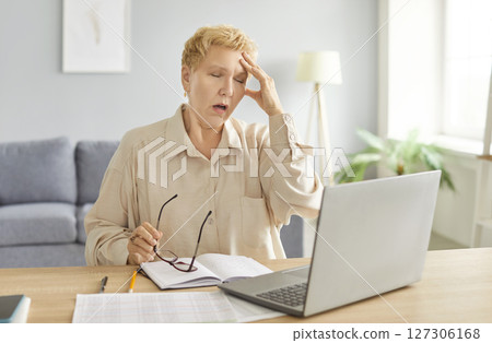 Mature tired unhappy freelance business woman in glasses sad working at home, laptop, typing Mature tired unhappy freelance business woman in glasses sad working at home, laptop, typing 127306168