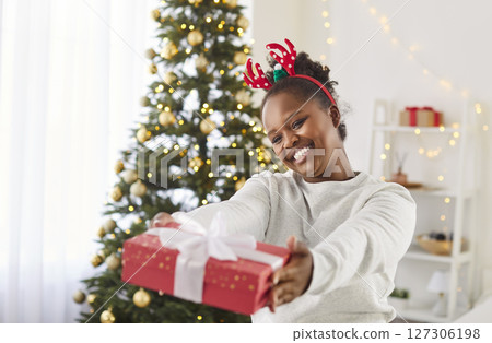 Young happy girl giving red present gift box at camera celebrating Christmas or New Year 127306198