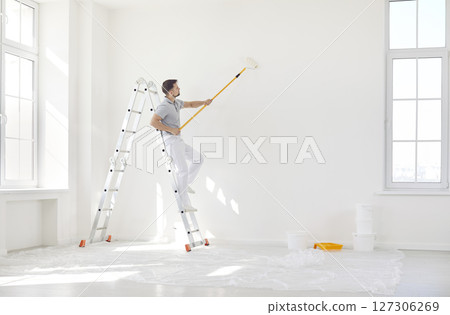 Male painter or construction worker painting wall surface in white color with paint roller brush Male painter or construction worker painting wall surface in white color with paint roller brush 127306269