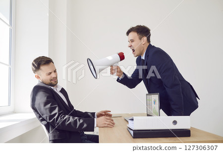 Angry boss with megaphone shouts at man in office, close-up 127306307