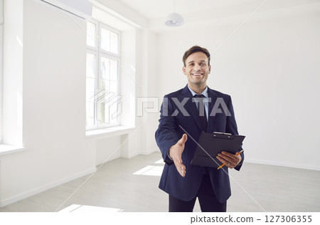 Portrait Of Happy Real Estate Agent Offering Handshake In Empty Home Or Office 127306355