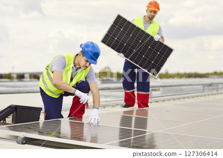 Two male workers repairing or installing solar panels on the roof. Two male workers repairing or installing solar panels on the roof. 127306414