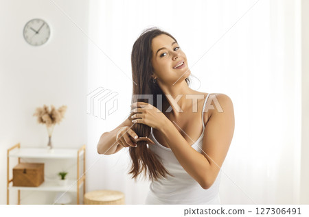 Young smiling beautiful woman brushing long healthy brunette hair, happy female doing morning beauty Young smiling beautiful woman brushing long healthy brunette hair, happy female doing morning beauty 127306491