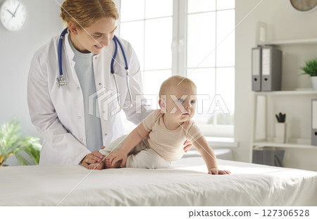 Pediatrician doctor examining cute little toddler child baby lying on couch in medical clinic 127306528