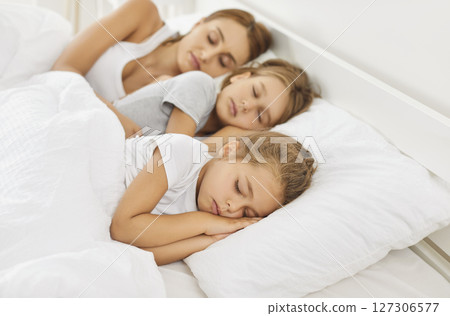 Mother sleeping in sweet dreams with children on bed in cozy white bedroom in the morning Mother sleeping in sweet dreams with children on bed in cozy white bedroom in the morning 127306577