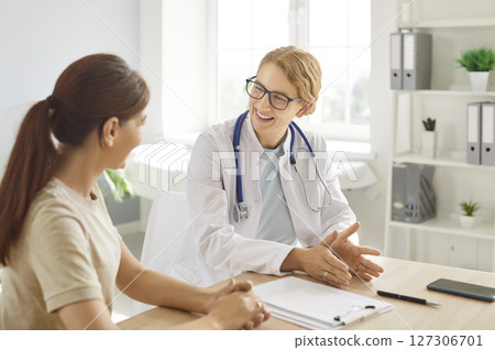 Smiling female doctor talking to patient in medical office, providing professional consultation. Smiling female doctor talking to patient in medical office, providing professional consultation. 127306701