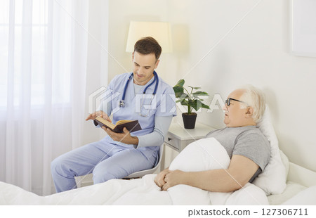 Caregiver Reading Book To Senior Patient During Leisure Time At Nursing Home Caregiver Reading Book To Senior Patient During Leisure Time At Nursing Home 127306711