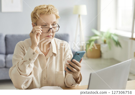 Serious focused woman, pensive lady using mobile phone for work at desk, communication, thinking 127306758