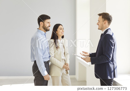 Man and woman talking with man realtor in new house and ready to become homeowners. 127306773
