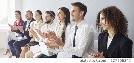 Young business people in formal clothes applauding to speaker sitting in a row in meeting room Young business people in formal clothes applauding to speaker sitting in a row in meeting room 127306843