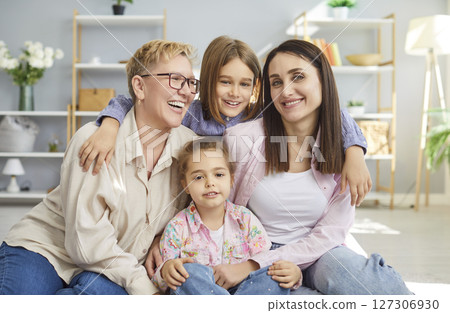 Positive grandmother, mother and two children embracing and feeling very glad have good relationship Positive grandmother, mother and two children embracing and feeling very glad have good relationship 127306930