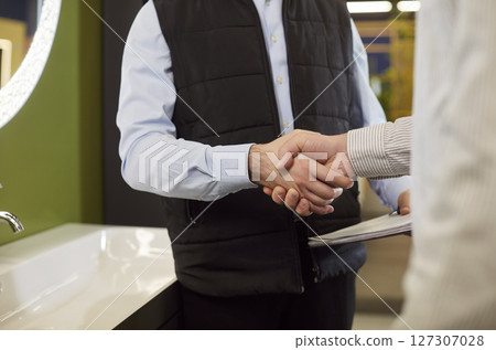Close-Up Of Salesman Handshaking Client In Store Close-Up Of Salesman Handshaking Client In Store 127307028