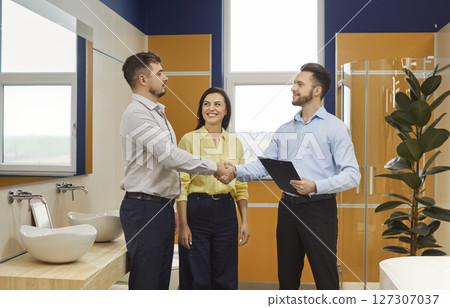 Couple Shaking Hands With Salesman In Plumbing Store Couple Shaking Hands With Salesman In Plumbing Store 127307037