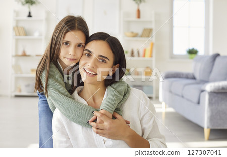 Portrait of smiling happy young mother with teen daughter looking at camera at home. Portrait of smiling happy young mother with teen daughter looking at camera at home. 127307041