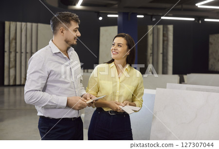 Sales manager consulting, helping, couple clients choose in showroom display of repair products 127307044