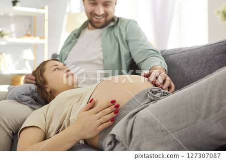 Loving happy couple young future parents expecting first baby on sofa close at home, caring husband Loving happy couple young future parents expecting first baby on sofa close at home, caring husband 127307087