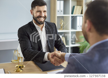 Male lawyer working in office shaking hand with a man client sitting at the desk on workplace 127307138