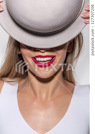 Beautiful woman with red lipstick hiding eyes with retro hat Beautiful woman with red lipstick hiding eyes with retro hat 127307206
