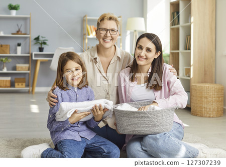 Happy family, three generations embracing beloved child, mom and grandma holding laundry basket Happy family, three generations embracing beloved child, mom and grandma holding laundry basket 127307239