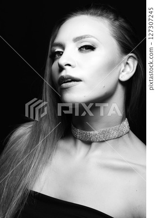 Beautiful brunette woman with black dress and fancy jewelry black and white studio portrait 127307245